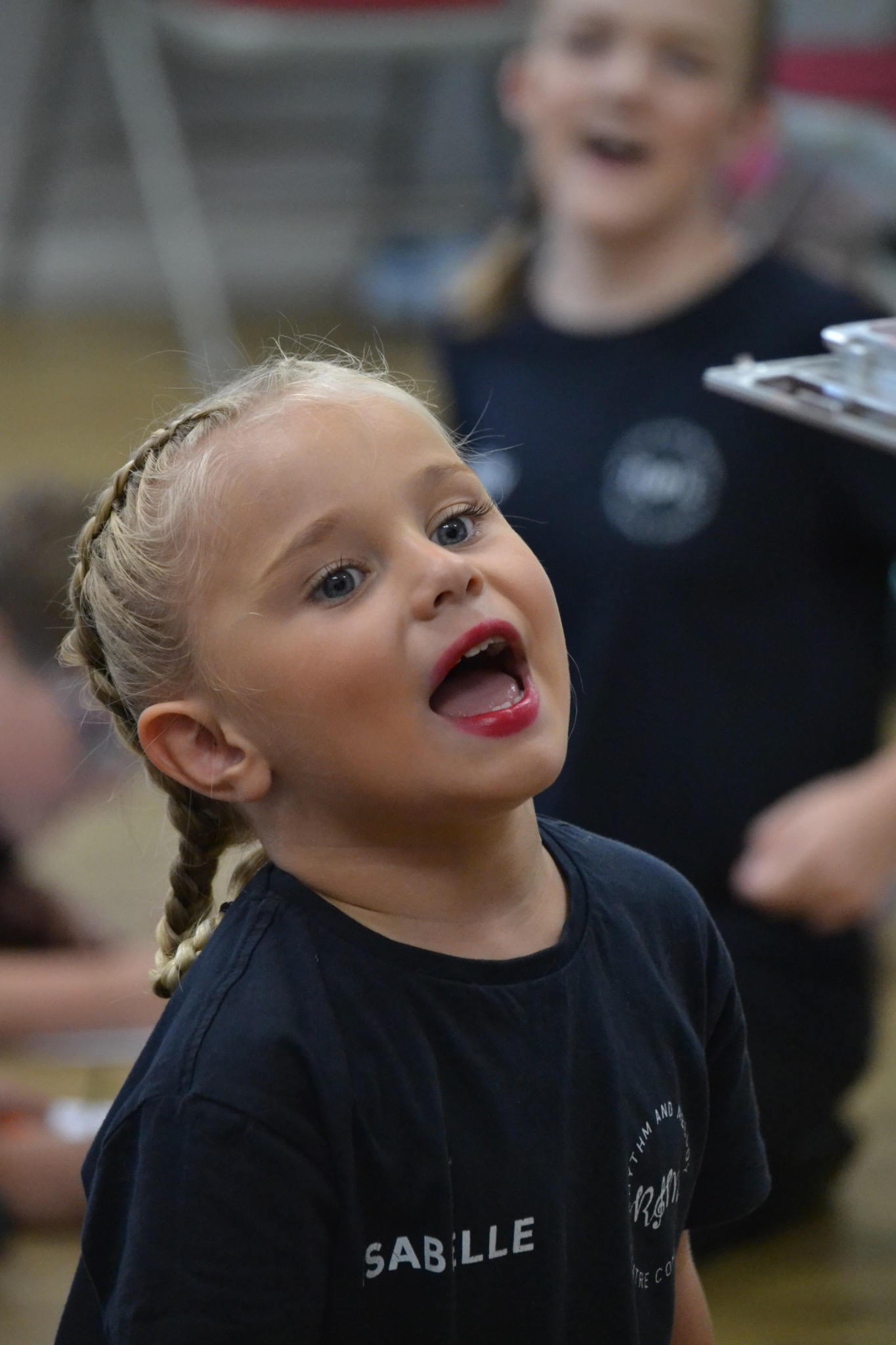 A young performer sings with other performers nearby.