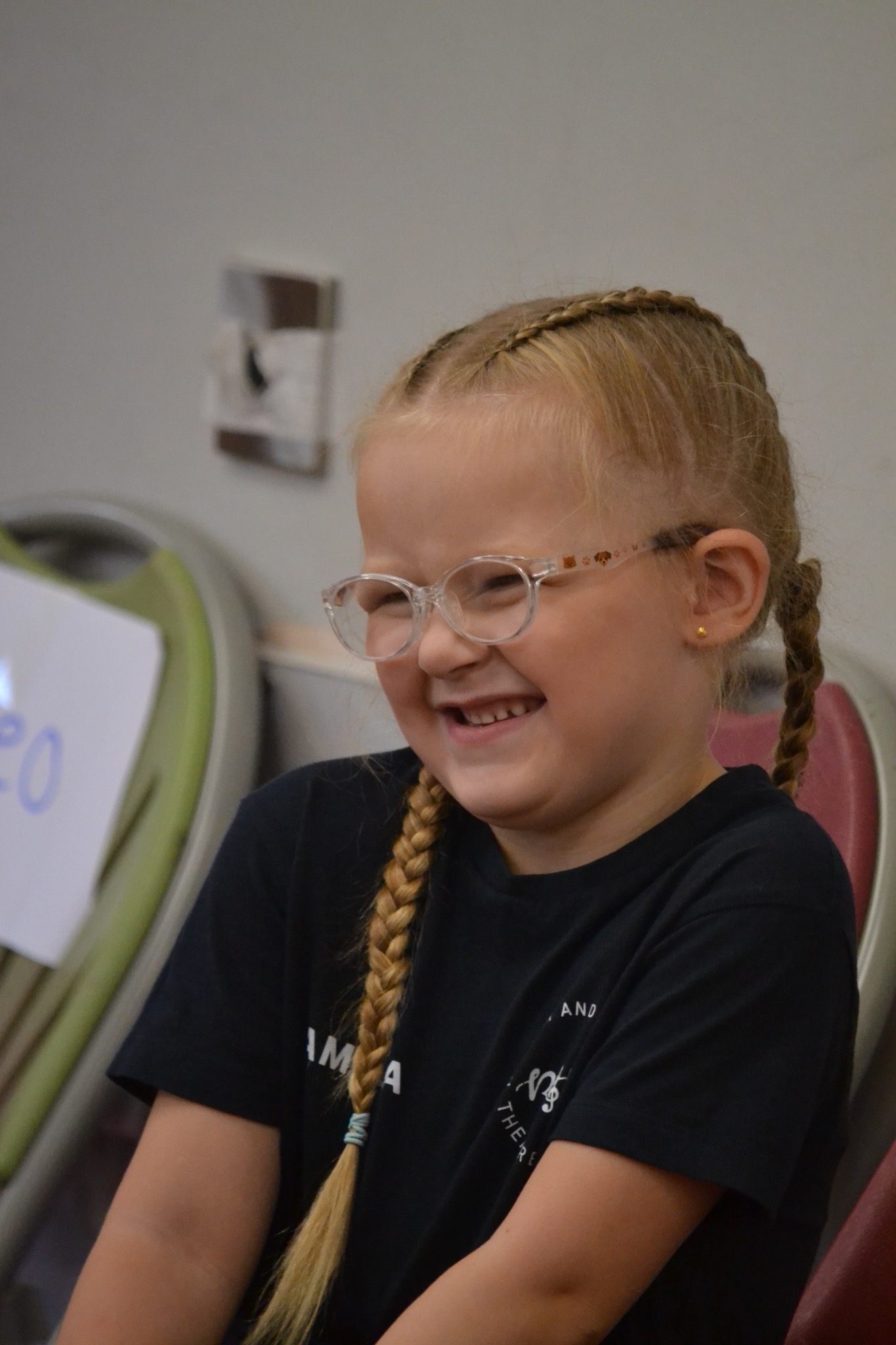 A young performer wearing glasses smiles while seated between activities.